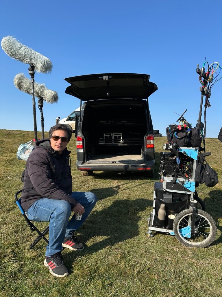 44 unit — sound cart and twin booms in an open field between takes