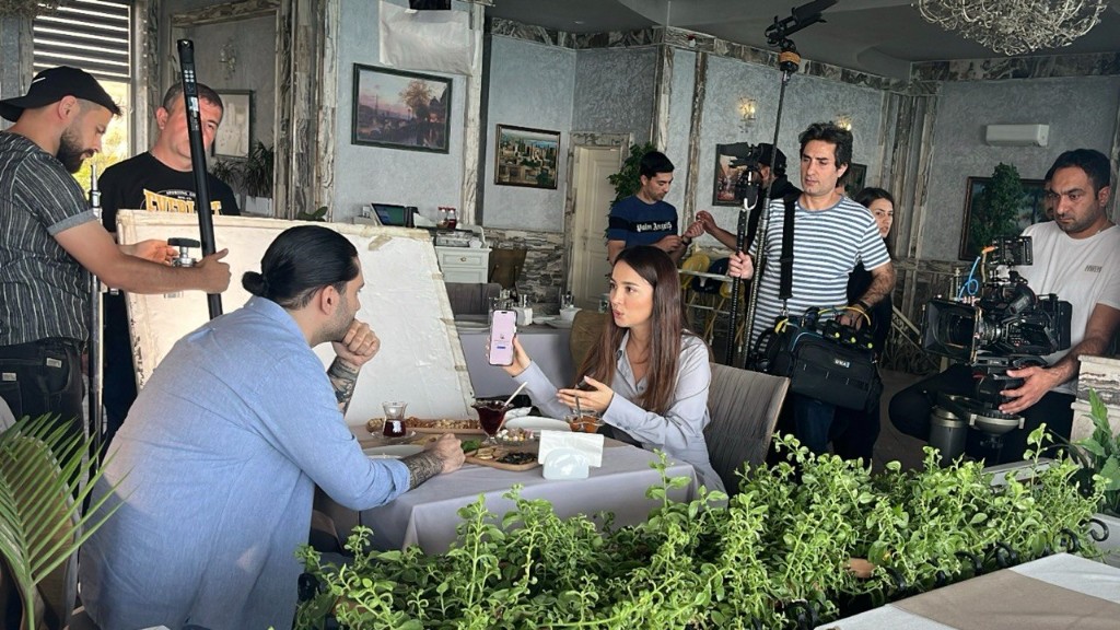 21-ci Möcüzə cafe interior — boom and camera covering a table dialogue