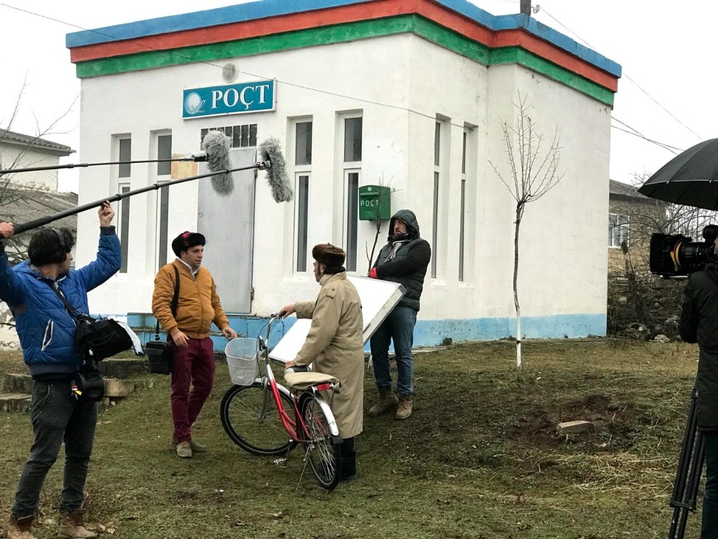 Boom operator covering actors at the Oxşarabad village post office with camera rolling