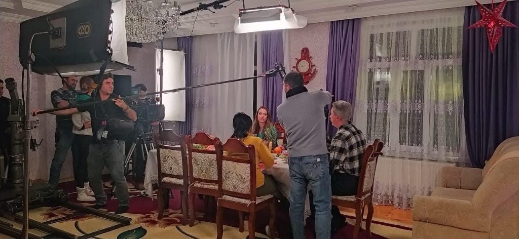 Sən demə set — boom over a lit dinner-table scene with the camera crew