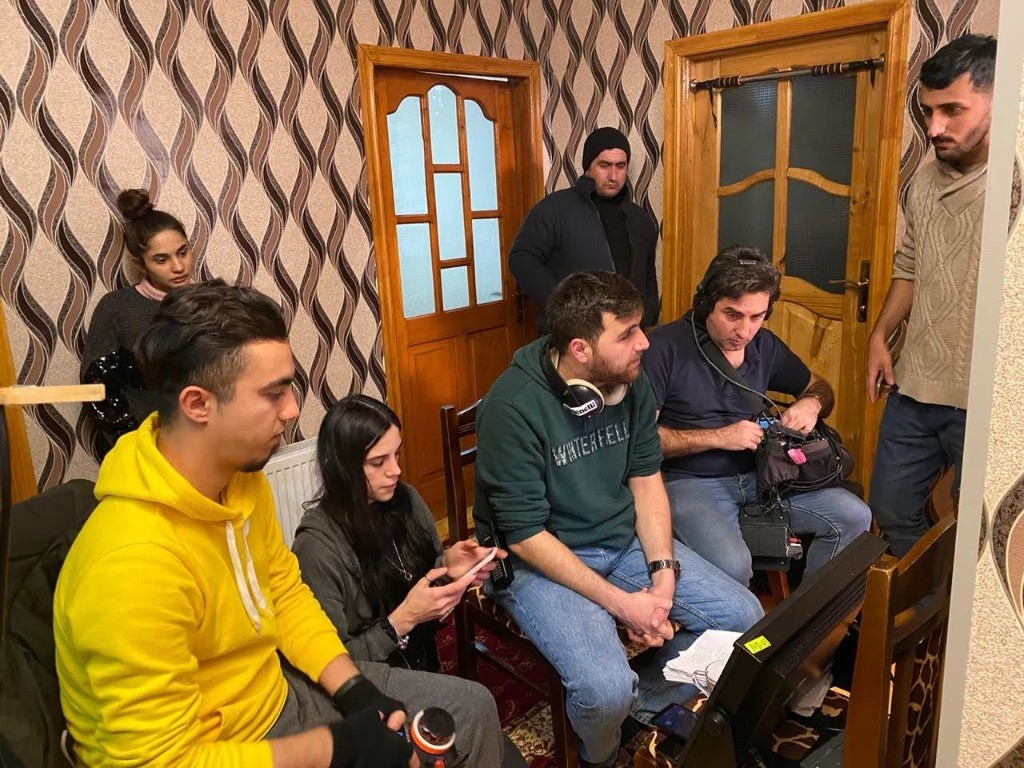 Sən demə crew at the monitor with the sound recordist on headphones between takes