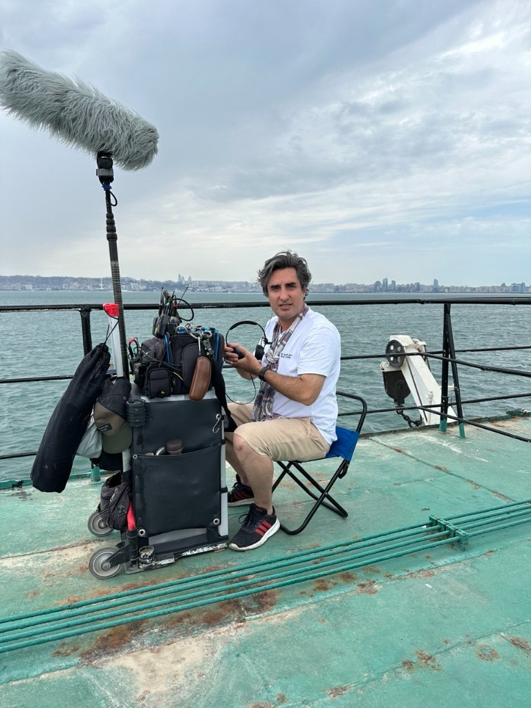 Morteza Najaflo with the sound cart and boom on the Şövkət ship deck, Baku skyline across the bay.