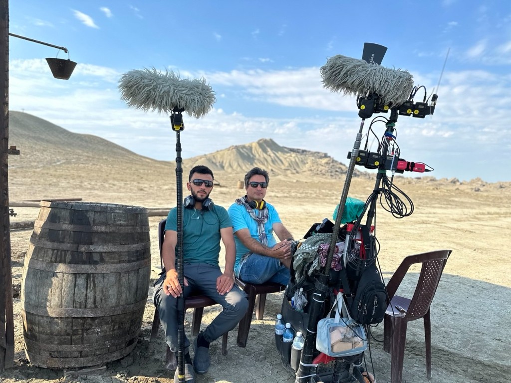 Sound team with cart and twin booms in open desert location