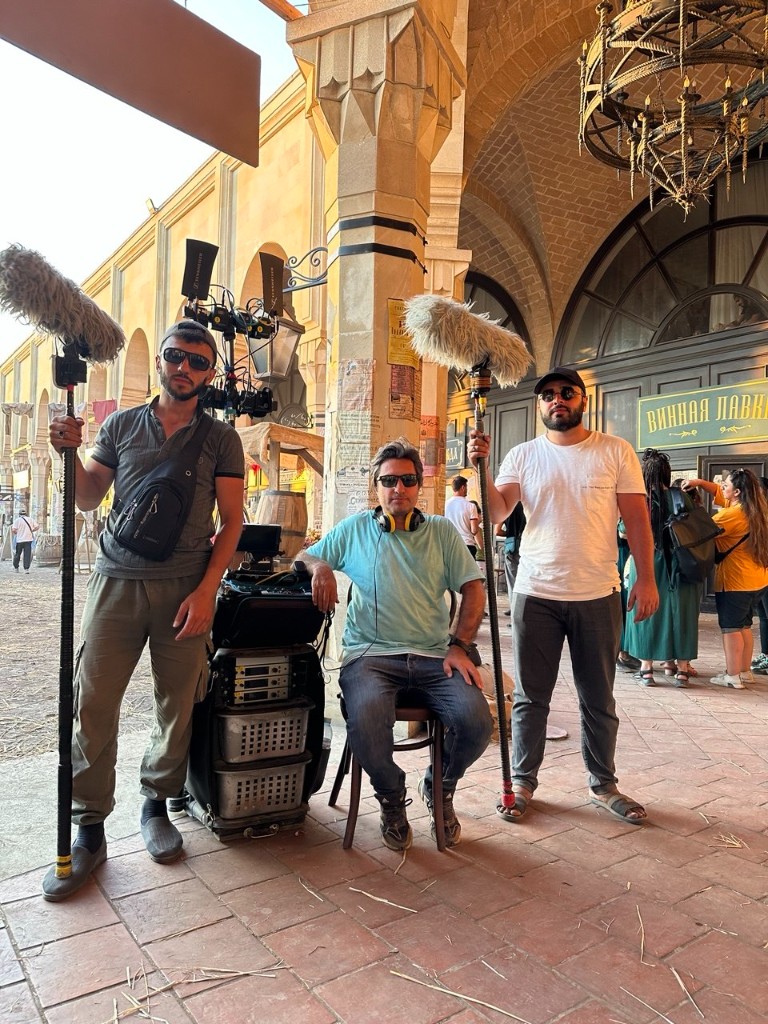 Three-person sound team with rack and booms under stone arches